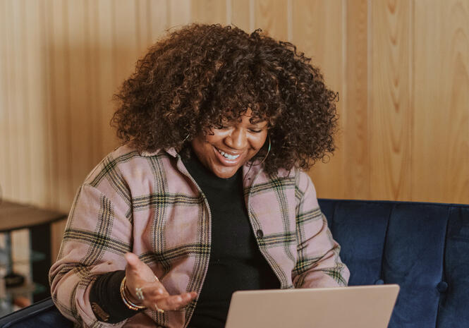 Woman smiling and speaking towards her laptop